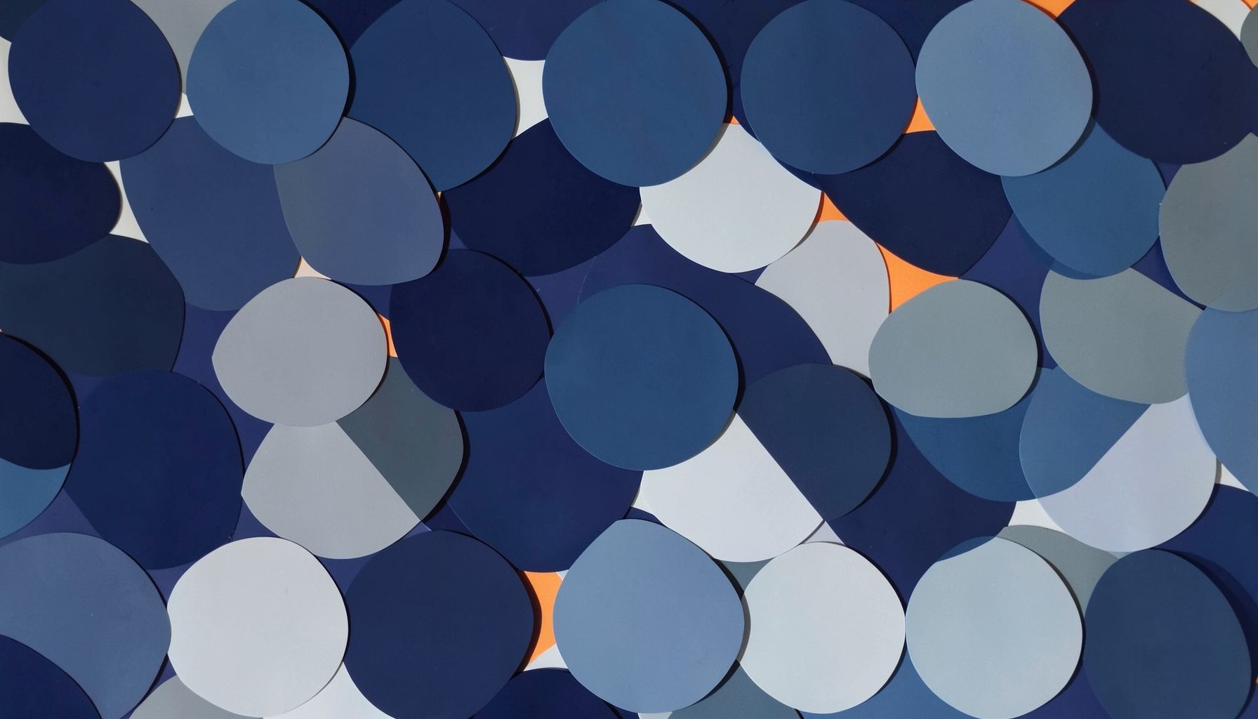 A simple geometric pattern of overlapping circles in navy, steel blue, and pale grey, with a single warm orange highlight.